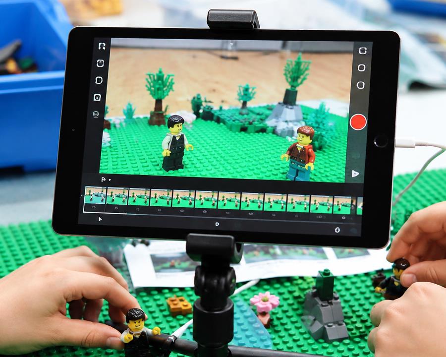 A tablet filming LEGO minifigures on a stop-motion animation set